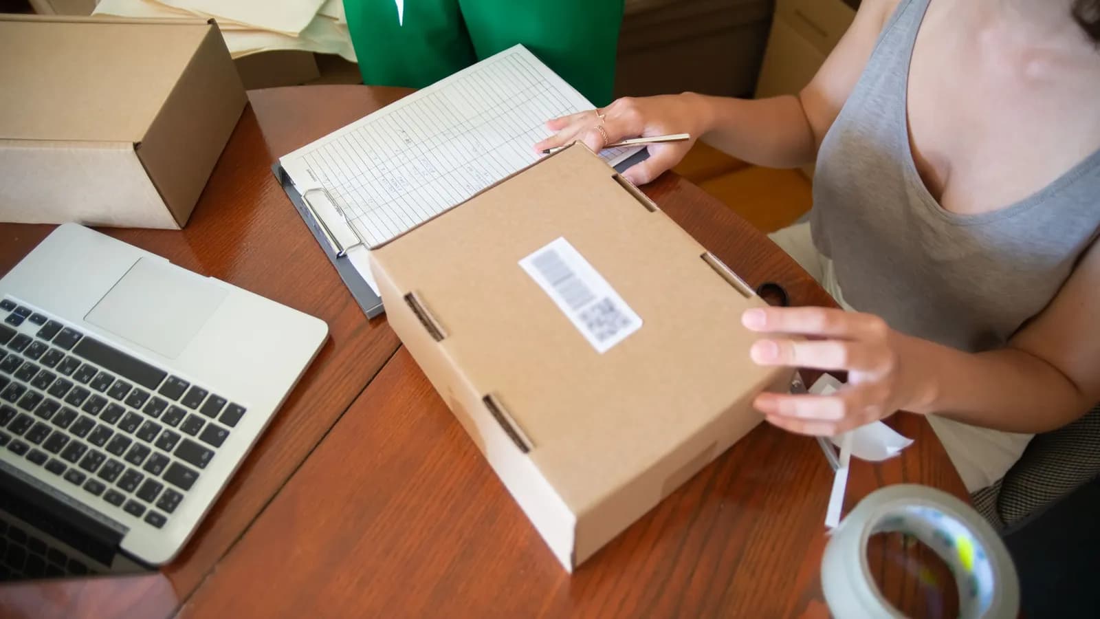 Người bán hàng online dán nhãn gói hàng cạnh laptop