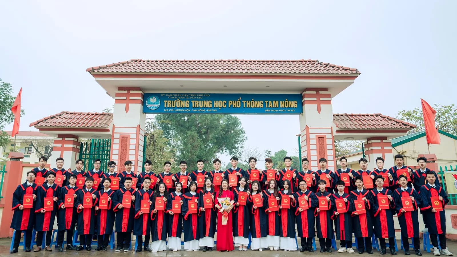 Một lớp học sinh chụp ảnh tốt nghiệp trước cổng trường