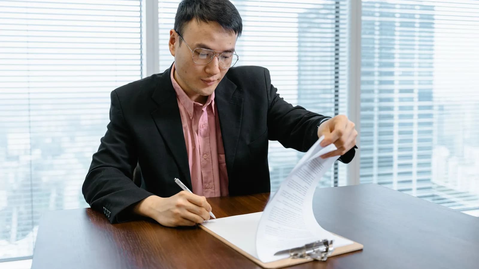 Người quản lý đọc và ký duyệt tài liệu ở bàn làm việc