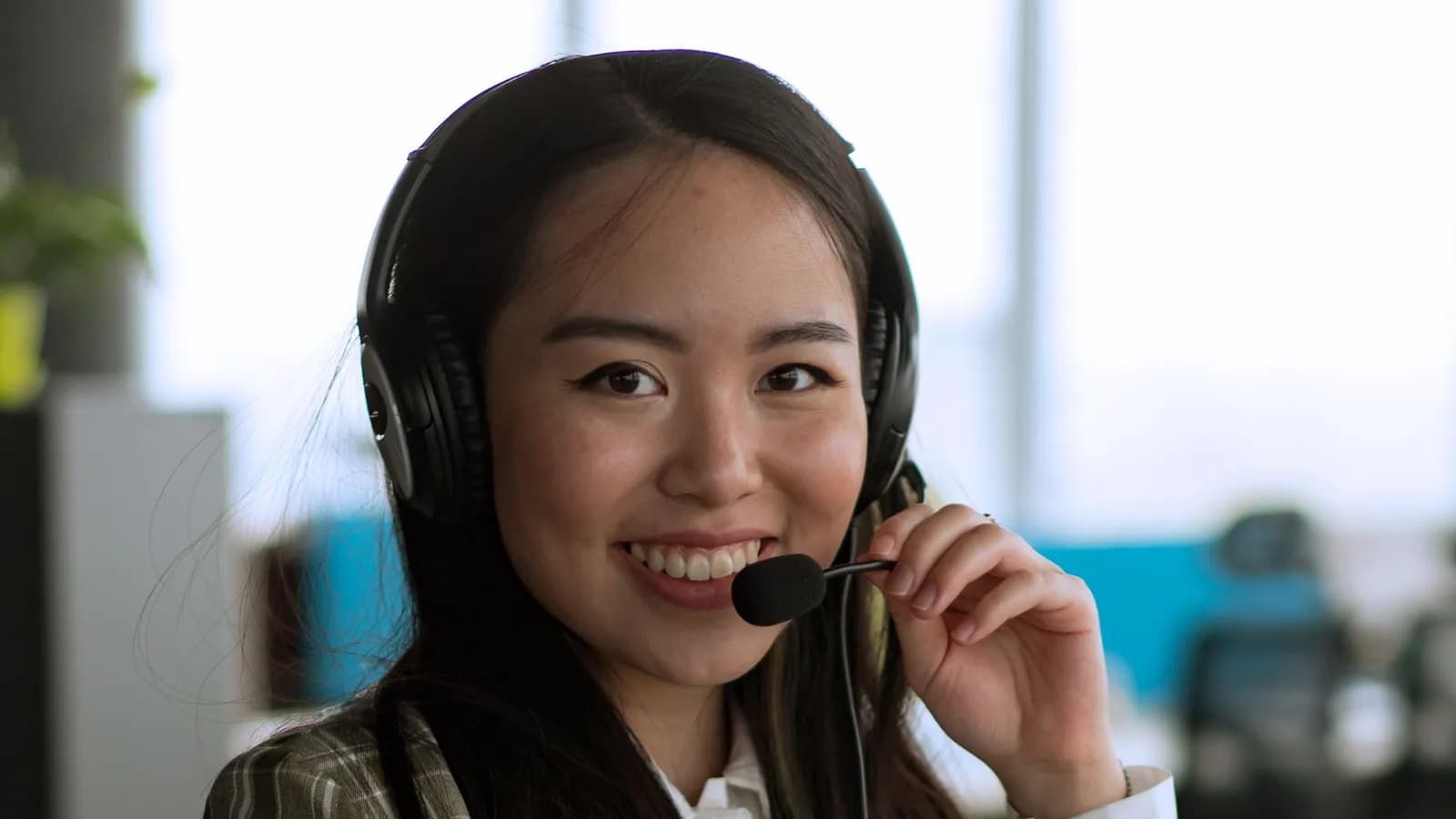 Nhân viên chăm sóc khách hàng đeo tai nghe mỉm cười tại văn phòng
