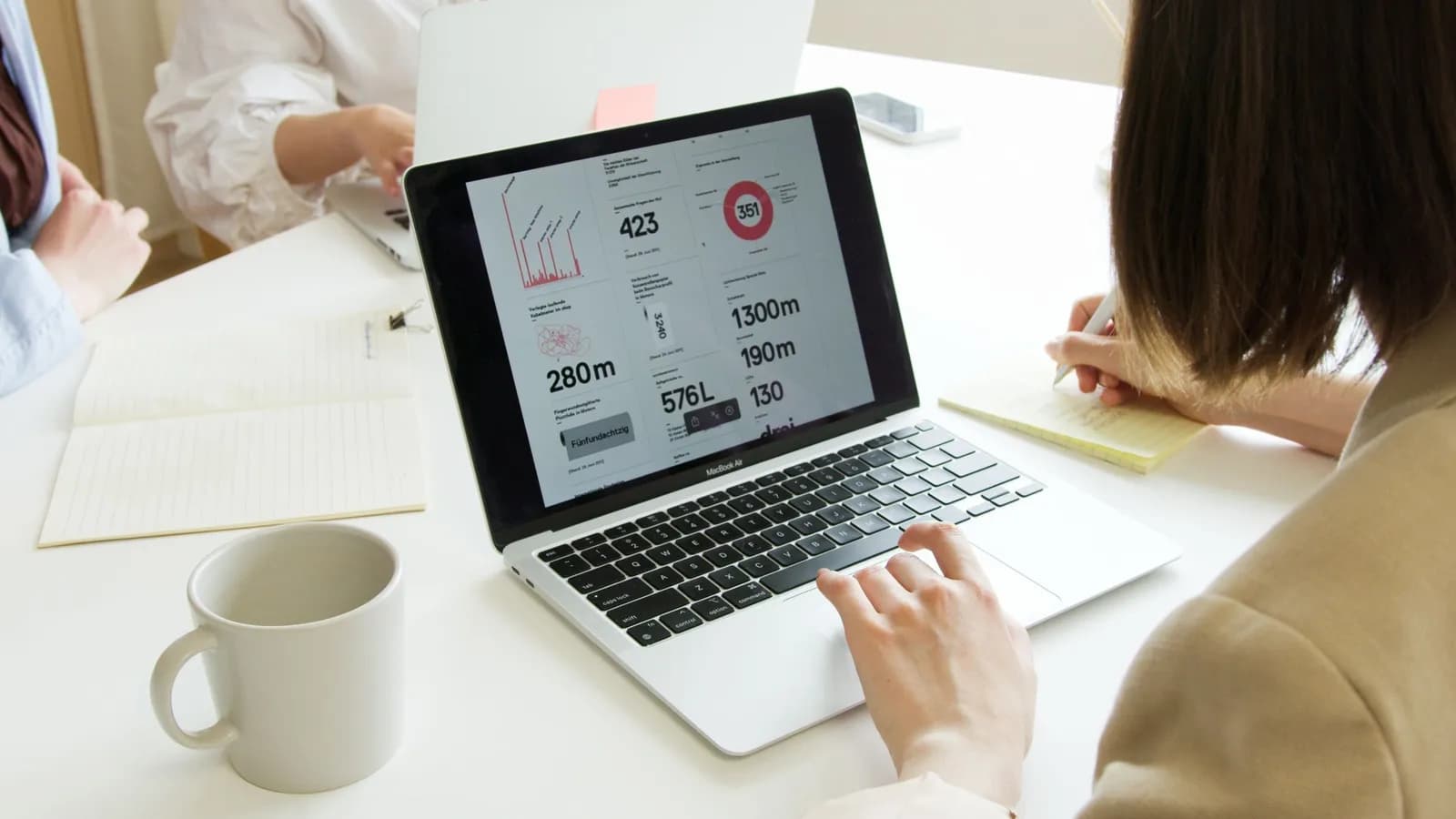 Laptop mở bảng số liệu với biểu đồ trên bàn làm việc có tách cà phê