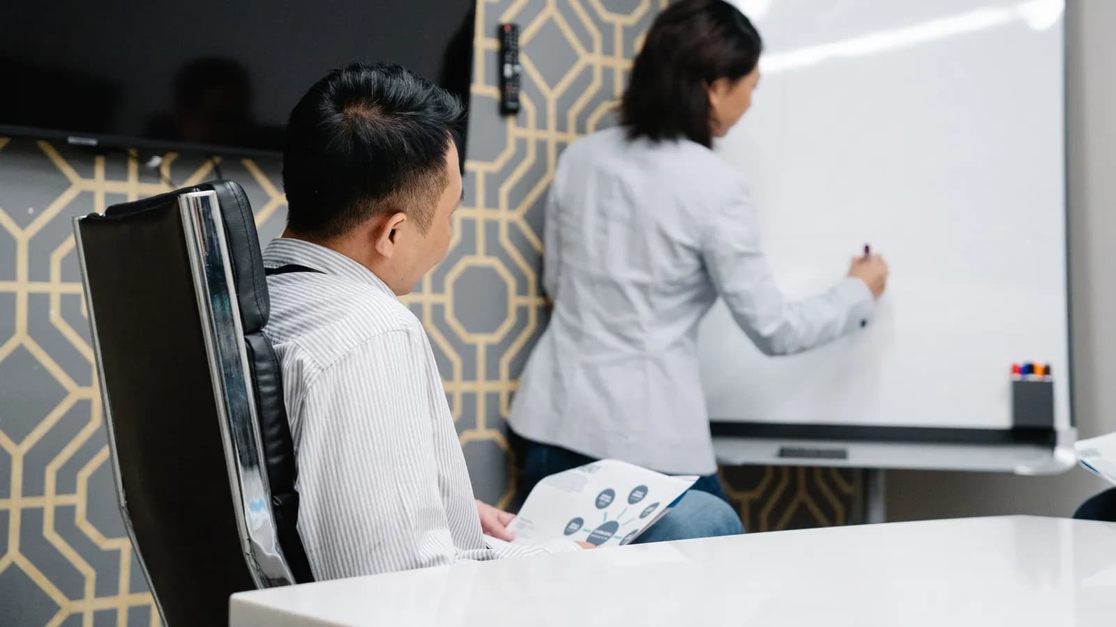Hai người phác kế hoạch marketing trên bảng trắng trong phòng họp nhỏ