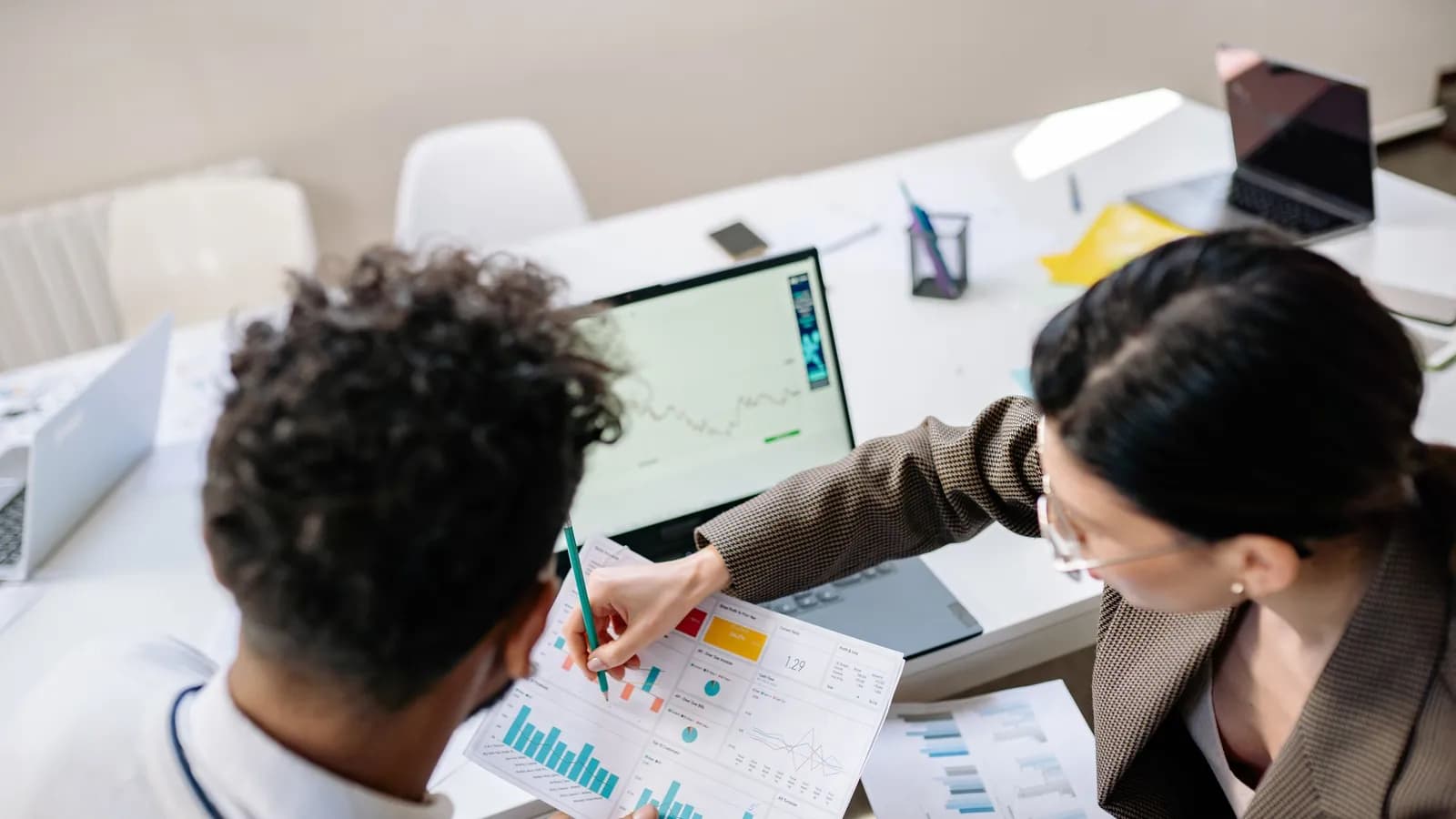Nhóm marketing xem biểu đồ hiệu suất trên laptop và bản in